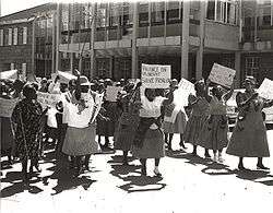 A black and white photo of dozens of protesters, some holding placards.