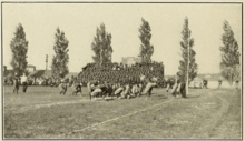 Men lined up in dark sweaters preparing for the beginning of a football play