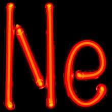 Photograph of glass tube that's been bent to form the connected letters "Ne". The tube is glowing brightly with a red color.