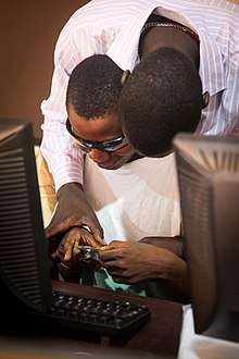 Dorothy Springer Trust (DST) volunteer, Nelson, supports visually impaired student, Osman, during a lesson.