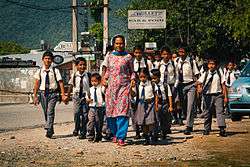 Teacher in Nepalese dress and a group of uniformed schoolchildren of different ages