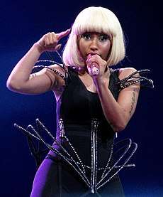 A picture of a woman wearing a black outfit with blonde hair singing