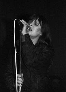 Nico singing into a microphone onstage