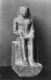 Small statue showing a king seated, wearing the nemes and clenching his right hand.