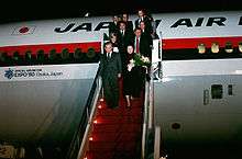 Japan Prime Minister Noboru Takeshita and 11 others deplane on steps in red colour, from a Japan Air Lines DC-10 marked with an Official Airline for Expo '90 Osaka, Japan logo and text