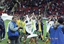 Footballers celebrating with a large cardboard fake trophy