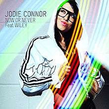 A portrait like a TV Show is Bommerang in a rainbow-like colour of a woman seductively posing with her jacket on her head. The Woman stands hand right and the black stands hand up on the rainbow colour. To the woman's left in black stands 'JODIE CONNOR NOW OR NEVER Feat. WILEY'.