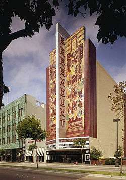An artist's depiction of a movie theater facade, showing its colorful tile mosaic design flanking a blade that reads "Paramount" over a wide marquee and street entrance.