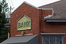 A portion of a brick building, with an aged sign saying "Bank."