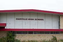 On the side of a gymnasium, the sign reads "Oakville High School."
