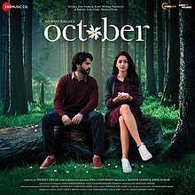 The soundtrck album cover features Varun Dhawan and Banita Sandhu seated on a wood log lying in a jungle. They appear wearing winter-seasoned clothes depicting the month of October. The album title appears at top.