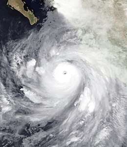A well developed hurricane approaching Baja California, Mexico, from the south. It features a mostly circular cloud mass surrounding a defined eye.