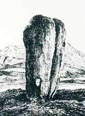  A black and white line drawing of a tall standing stone that is wider at the top than the base. It has a long vertical crack on the right-hand side and there is a small hole that goes right through it near the ground. A lake and hill are in the background.