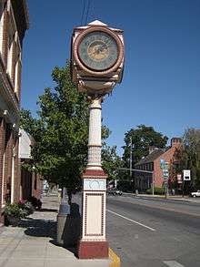 Street clock and (at right) post office. The legend on the clock says "Live better electrically." The post office is listed on the National Register of Historic Places.
