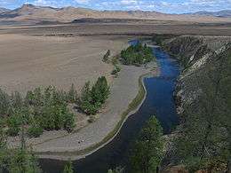 River running through a desert landscape. There are some trees near the river.