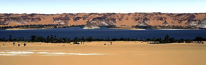 A lake in a desert area, surrounded by sandstone formations.