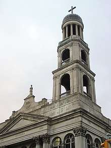 Three-tiered bell tower with arches on each tier. At the top is a dome with a cross