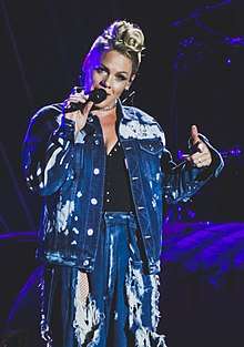 Pink with short platinum hair singing with a microphone