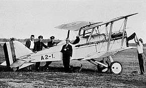 Side view of single-engined biplane surrounded by five men
