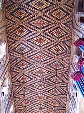 This wooden ceiling is painted in red, yellow and brown with figurative motifs framed in diamond shapes