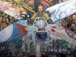 The central scene. A workman is depicted controlling machinery. Before him, a giant fist emerges holding an orb depicting the recombination of atoms and dividing cells in acts of chemical and biological generation.