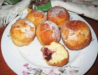 Six fried pampushky on a plate. Cherry filling is visible in one of them