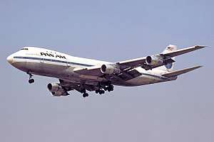 A Pan Am 747-100 in white and blue livery during final approach with its landing gear extended. The aircraft is N732PA, the third 747 built and an aircraft that was used in the 747 flight test program.