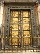 A pair of large bronze doors, with ornate frames. The doors are divided into ten rectangular sections with decorations between them. Each section contains a relief sculpture telling a story from the Old Testament. The panels and parts of the frames are covered with gold.