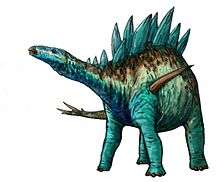 A long-necked dinosaur standing on four legs. The back has numerous bony plates extending upward.