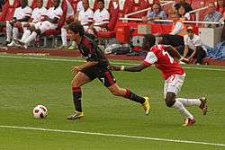 A colour photograph of Milan footballer Alexandre Pato on the ball, chased by opponent Emmanuel Eboué.