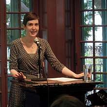 A caucasian woman with short hair lecturing at a podium