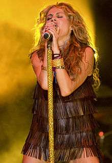 Paulina Rubio, a young, blonde woman, sings into a microphone onstage
