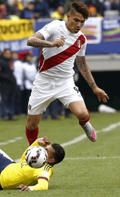 Photo of a man, wearing all-white uniforms marked by a red diagonal stripe in their jerseys, contesting a football