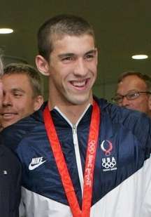 Michael Phelps with a gold medal hung around his neck on a red ribbon