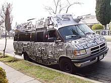 A parked van decorated with electronics and spray painted silver.