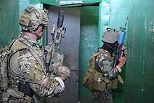 Colour photo of two soldiers armed with rifles inside a building
