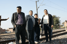 Four people standing next to a railroad track