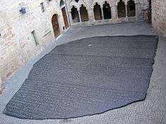 Photo depicting a large copy of the Rosetta Stone filling an interior courtyard of a building in Figeac, France
