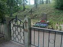 A modest tombstone, with flowers in front of it and an iron fence surrounding it is the gravesite for Red soldiers and civilians in Helsinki.