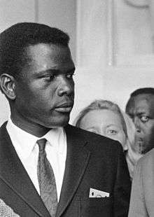 Black and white photo of Sidney Poitier in 1963—a black man about 33 years of age wearing a suit.