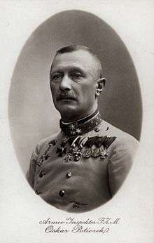 A male with a moustache wearing medals and a military uniform.