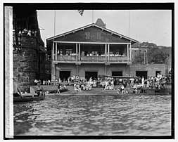 Potomac Boat Club from the Potomac River with various rowers standing outside Club building