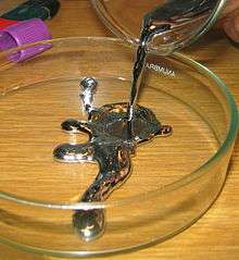 A dark viscous liquid being poured onto a glass surface