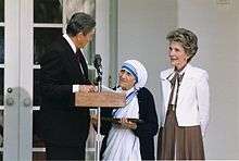 President and Mrs. Ronald Reagan with Mother Teresa, standing at a microphone