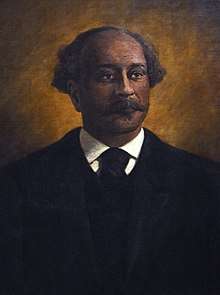 Painted bust-length portrait of a black man with a mustache and slight tuft of facial hair at his lower lip, wearing a black suit and necktie against an illuminated gold background. His head is bald at the top with locks of greyed curly hair sticking out on both sides of his head behind his temples