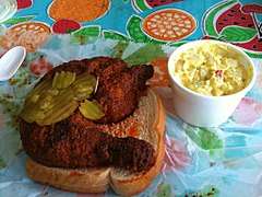 Hot chicken sitting on a piece of bread alongside other toppings and condiments