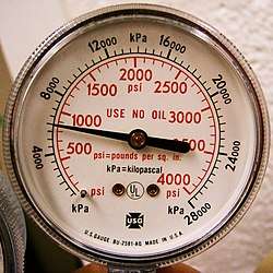  The face of a portable cylinder pressure gauge calibrated in pounds per square inch in red and kilopascal in black.