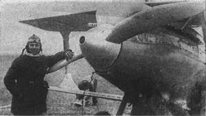 Old photo of pilot standing next to R-1 racer airplane