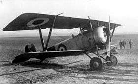 Single-engined military biplane parked in a field