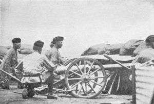 Three artillery men crouch behind a small 2.5&nbsp;inch "Screw Gun" employed in the defence of Kimberley